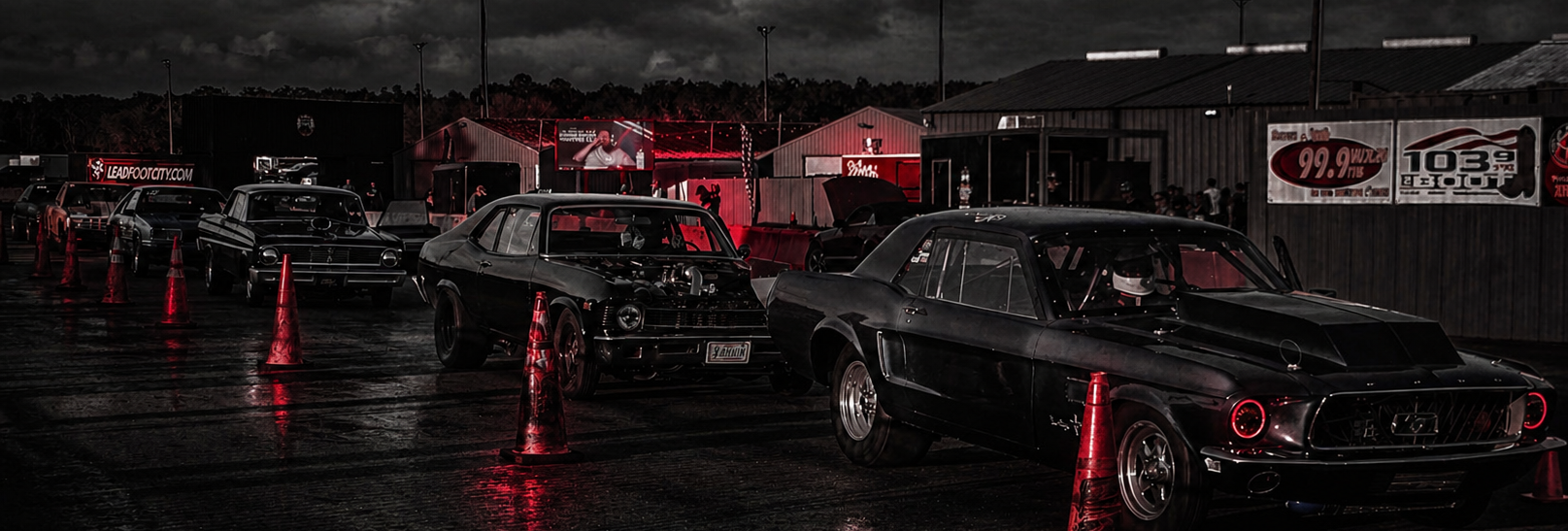 Vintage cars on a track with dark sky and wet ground